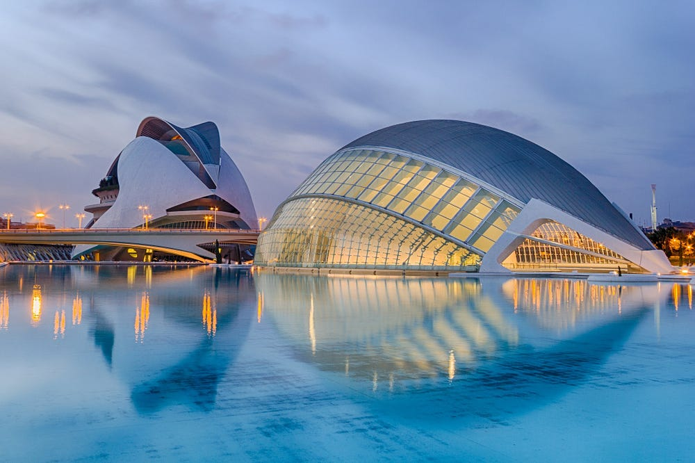 Serene modern architecture reflected on calm waters under twilight sky.