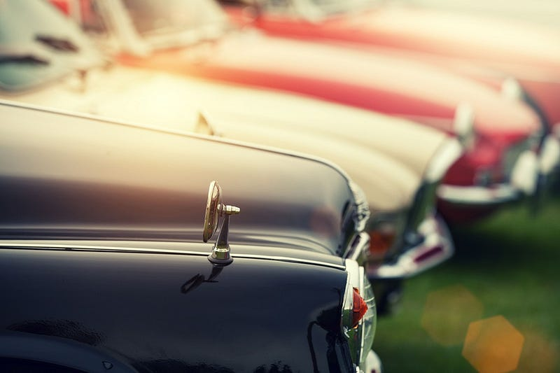 Vintage cars gleam in sunlight, showcasing classic charm and meticulous maintenance for enthusiasts.