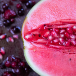 Fresh watermelon and pomegranate seeds on dark background, vibrant colors and textures.