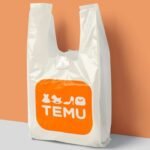 White plastic shopping bag with orange TEMU logo on peach and gray background.