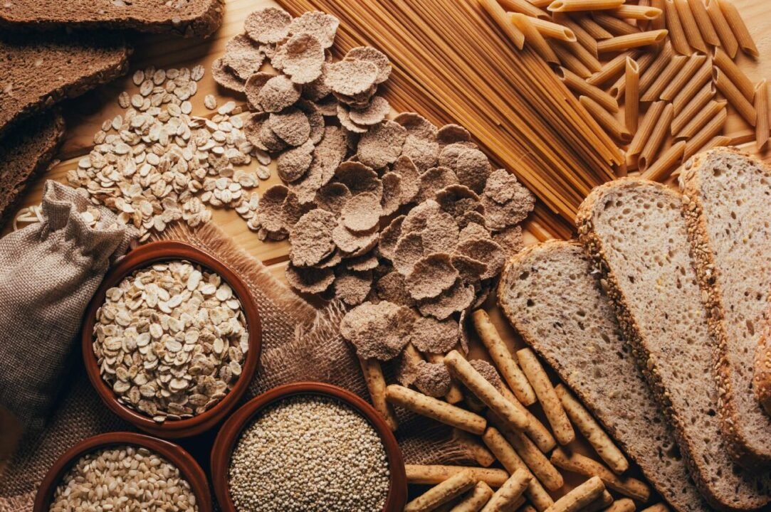 Nutritious whole grain bread, pasta, oats, and grains on wooden surface.