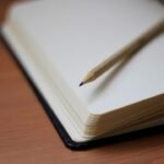 Minimalist pencil and notebook on wooden table, inviting creativity and contemplation.