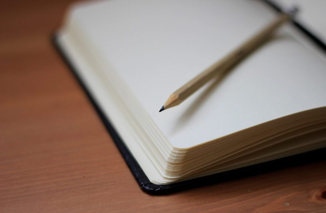 Minimalist pencil and notebook on wooden table, inviting creativity and contemplation.