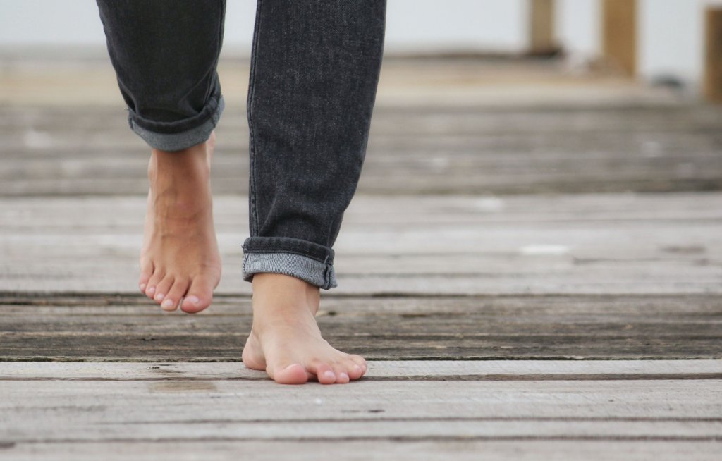 Casual stroll on wooden boardwalk, bare feet in rolled-up jeans.