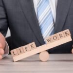 Balancing work-life with a seesaw metaphor: wooden blocks spell LIFE and WORK.
