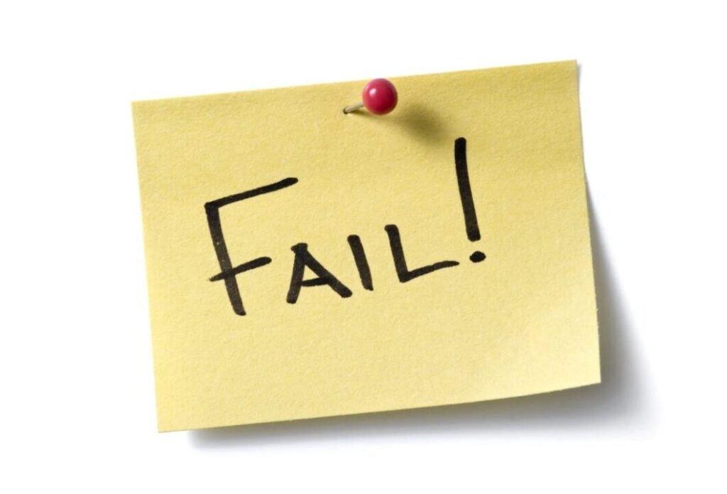 Yellow sticky note with the word "FAIL!" written in capital letters, pinned with a red pushpin.