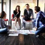 Young professionals brainstorming in modern rustic workspace with documents and charts.