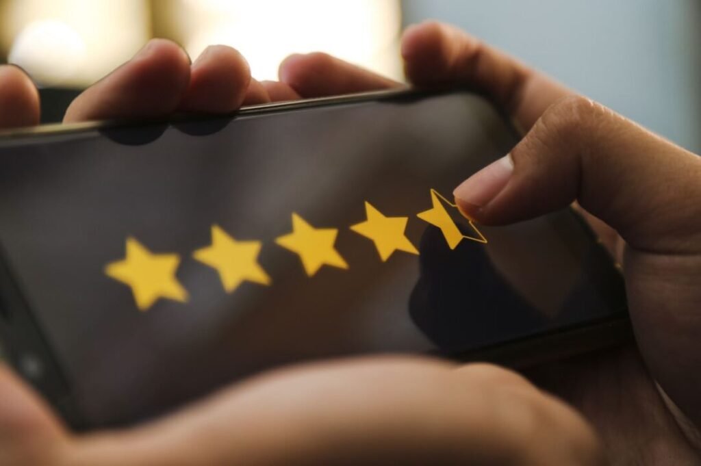 Hand holding a phone with a finger selecting a five-star rating.
