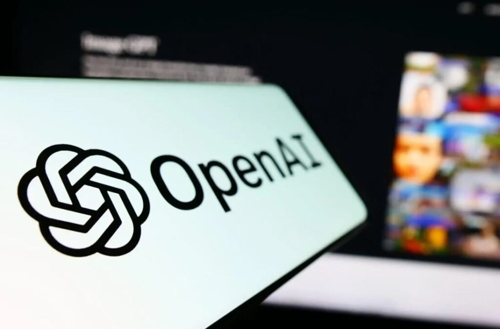Close-up of a screen displaying the OpenAI logo, with a blurred digital display in the background.