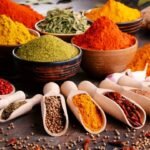 Colorful spices and herbs on rustic table create visually appealing culinary array.