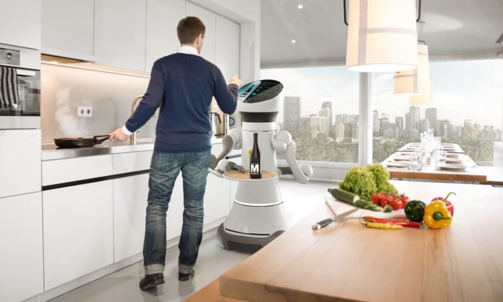 A man cooking in a modern kitchen interacts with a robot equipped with a touchscreen. The kitchen overlooks a cityscape, and fresh vegetables are laid out on a counter.