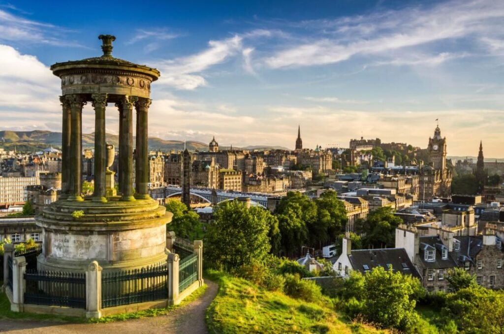 Aerial view of Edinburgh with Dugald Stewart Monument in the foreground and the cityscape including Edinburgh Castle in the background during sunset.