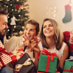 Celebrating Christmas with friends: joyful gift exchange in front of decorated tree.
