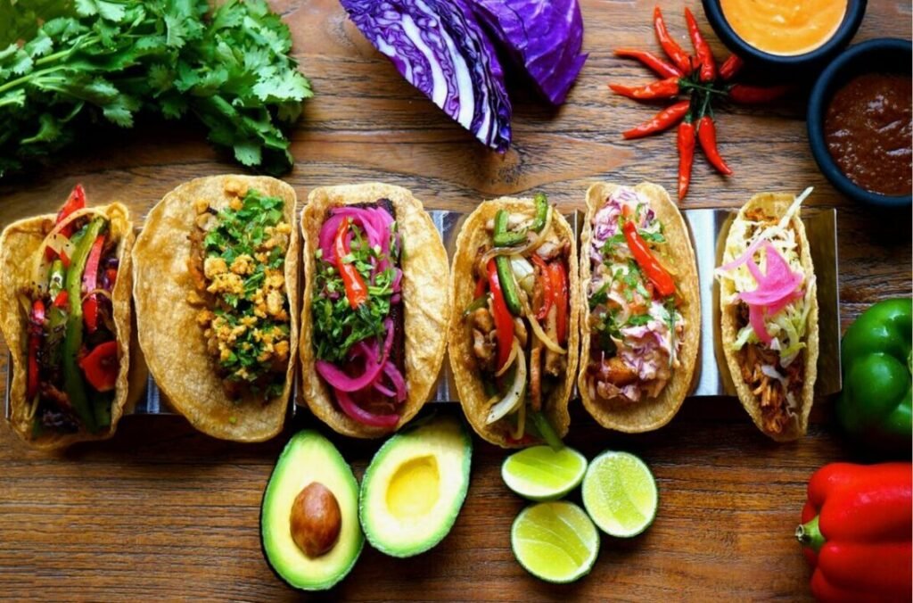 Delicious variety of Mexican tacos with fresh and colorful ingredients on wooden surface.