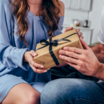 A warm gift exchange between a man and woman in a cozy living room.