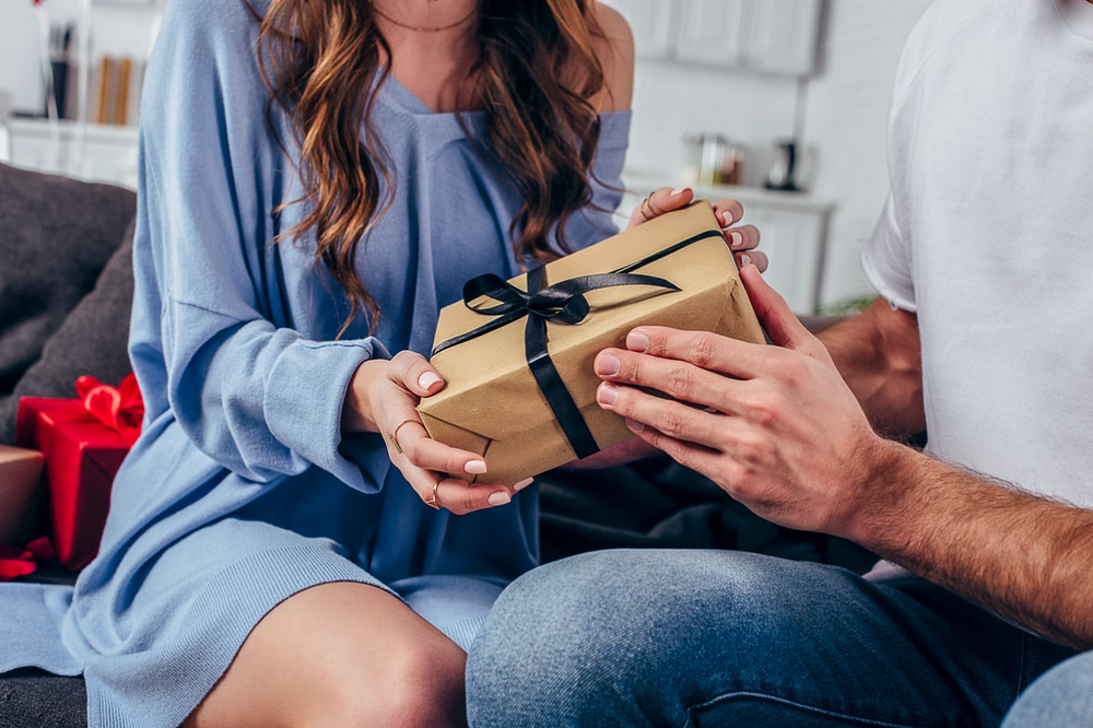 A warm gift exchange between a man and woman in a cozy living room.