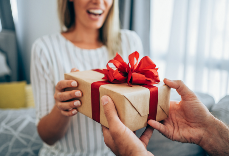 Heartwarming gift exchange between woman and older adult in cozy setting.