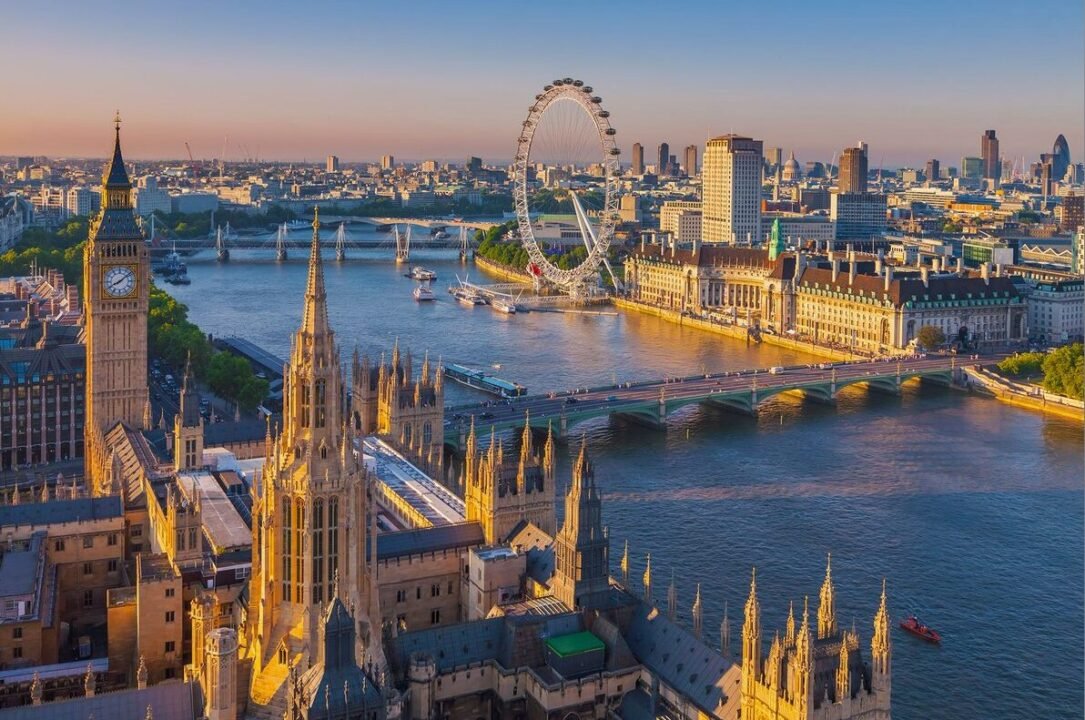 Aerial view of London featuring the Palace of Westminster, Big Ben, Westminster Bridge, the River Thames, and the London Eye.