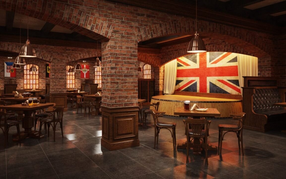 Cozy pub interior with wooden and brick decor featuring a stage with a large British flag, tables, chairs, and dim lighting.