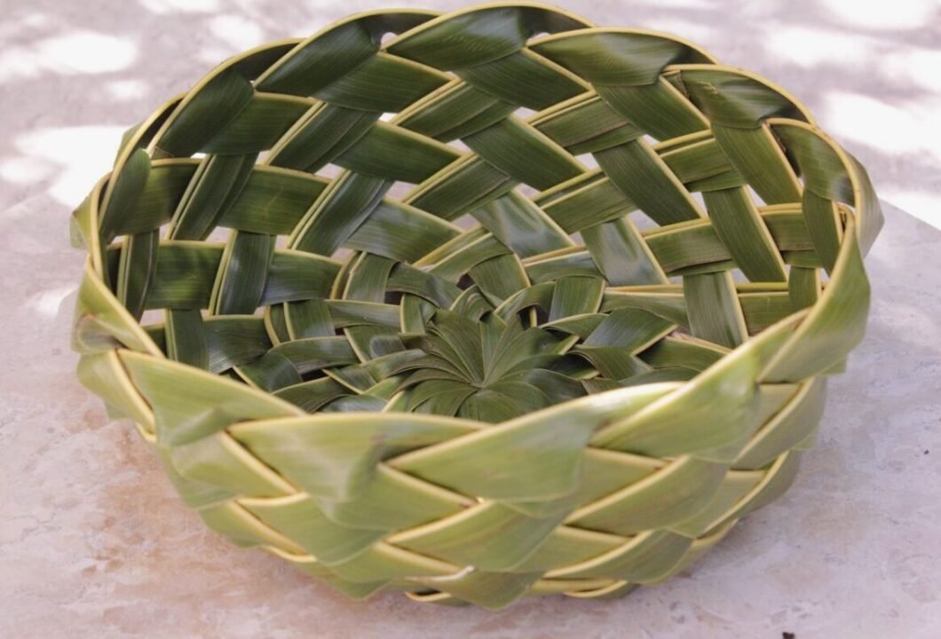 Woven green palm leaf basket on a light-colored surface.