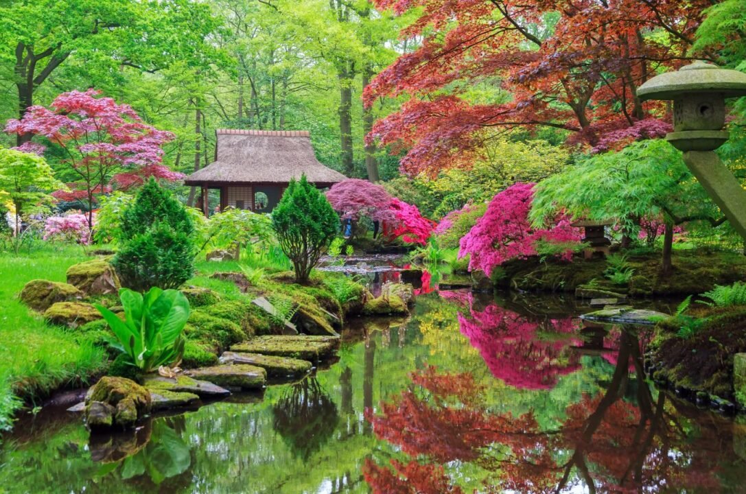 Tranquil Japanese garden with vibrant flowers, lush greenery, a thatched-roof tea house, and a serene pond reflecting the colorful foliage.
