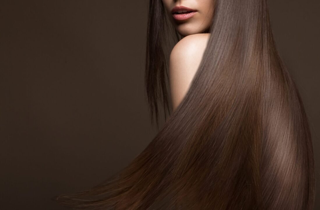 Woman with long, straight brown hair covering her back and side profile, against a neutral background.