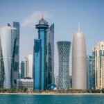 Stunning waterfront skyline with modern skyscrapers reflecting on calm blue water.