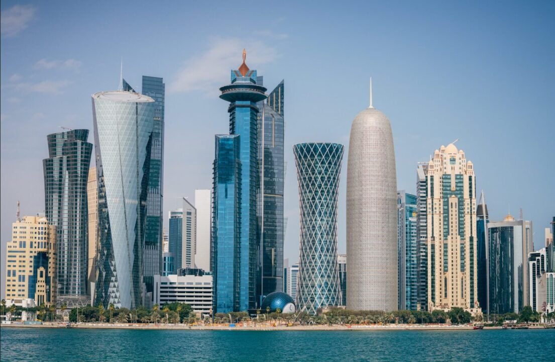 Stunning waterfront skyline with modern skyscrapers reflecting on calm blue water.