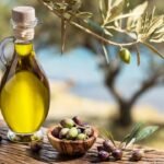 Rustic Mediterranean still life with olive oil, olives, and olive branches on wooden table.