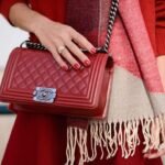 Stylish red quilted shoulder bag with matching coat, cream scarf, and coordinated accessories.