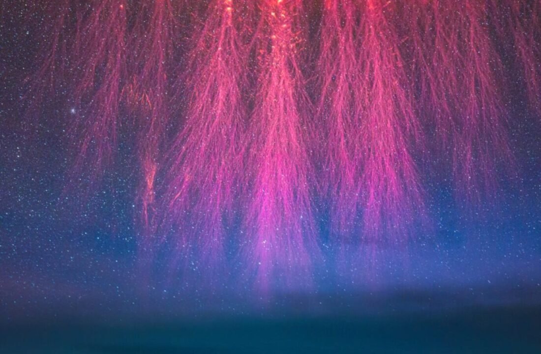 Aurora Borealis illuminating night sky with pink and violet lights and twinkling stars.