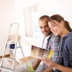 Couple happily choosing paint colors together in bright room, DIY home improvement.
