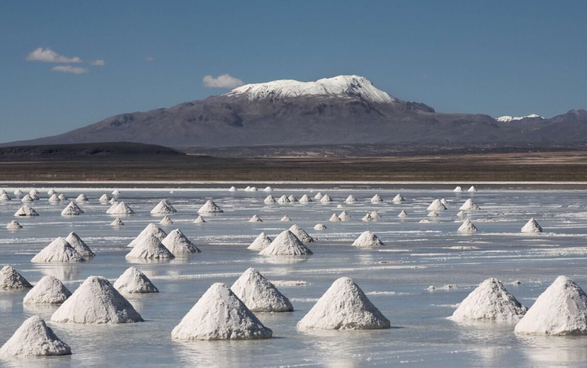 Majestic salt cones on a reflective flat with snow-capped mountains in the background.