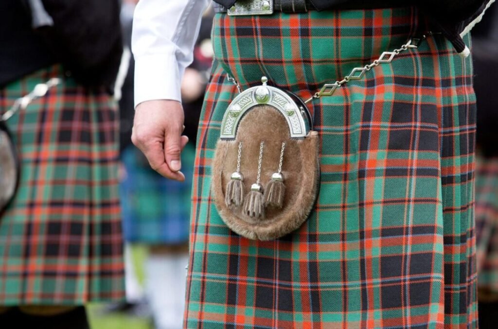 Close-up of men wearing traditional Scottish kilts with tartan patterns and a sporran at a cultural event.