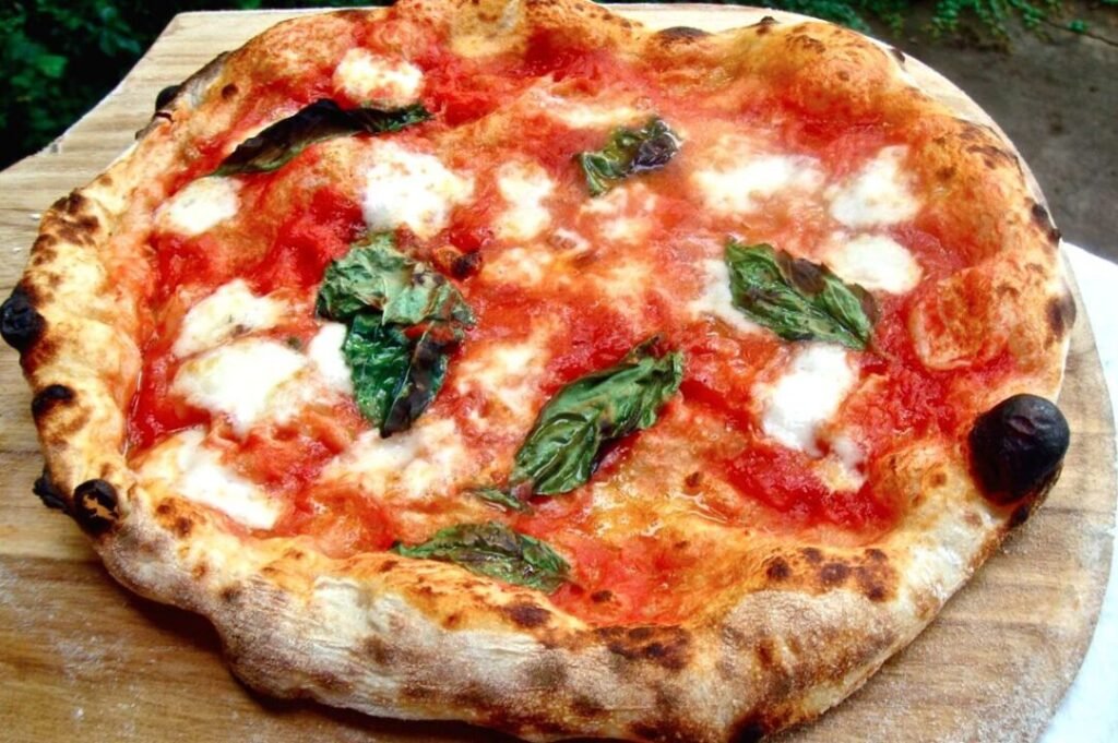 Neapolitan Margherita pizza with charred crust, fresh mozzarella, tomato sauce, and basil leaves.