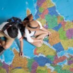 Children exploring colorful world map, pointing with curiosity.