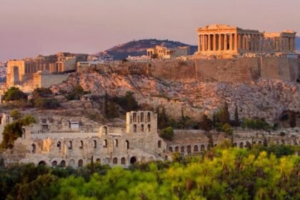 View of the Acropolis in Athens, Greece, featuring the Parthenon illuminated by sunset.
