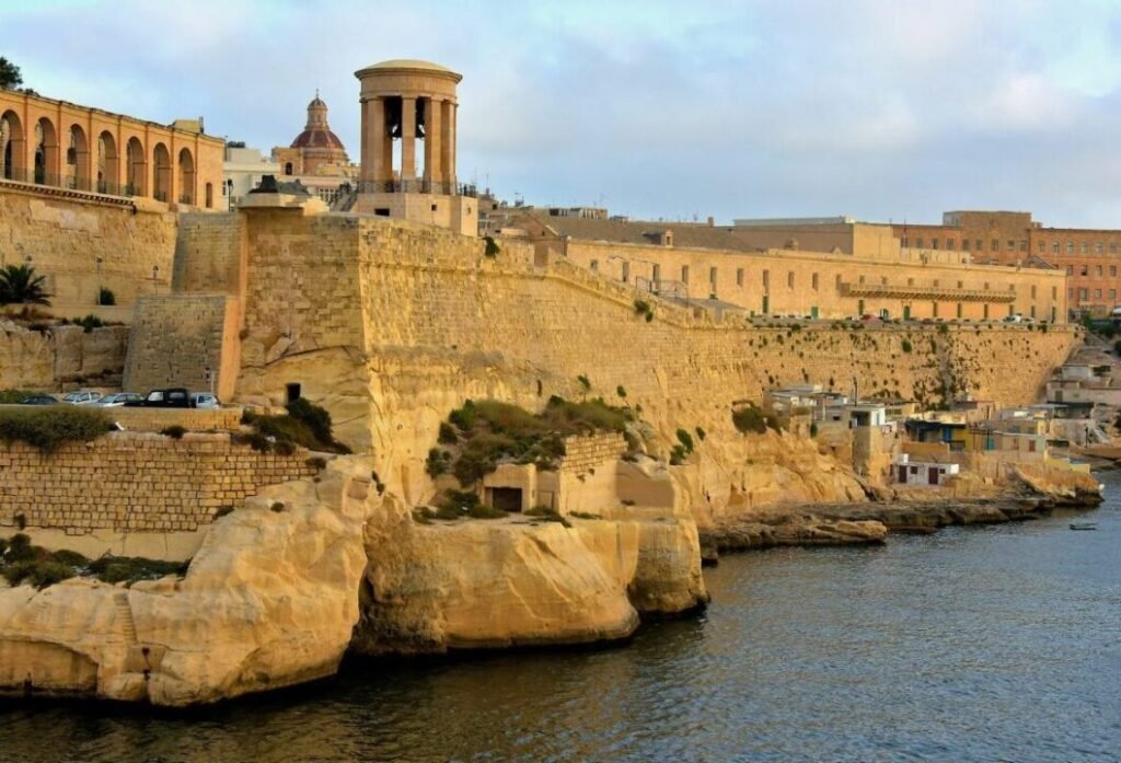 Historic stone fortifications and buildings by the seaside under a clear sky.