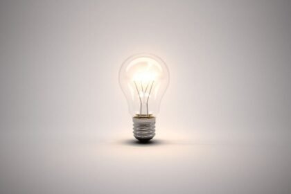 A glowing light bulb on a plain, white background.