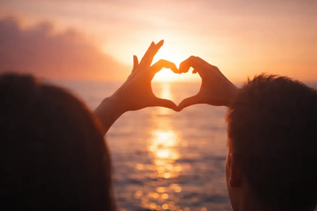 Love and relationship concept - two hands making a heart shape during a sunset